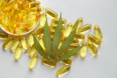 Tıbbi esrar ürünleri, yaprak, kapsüller beyaz arka planda CBD yağı. Biyolojik bitkisel bitkilerle birlikte jelatin softgeller. Organik beslenme takviyeleri kavramı