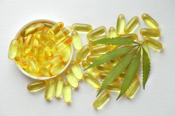 Tıbbi esrar ürünleri, yaprak, kapsüller beyaz arka planda CBD yağı. Biyolojik bitkisel bitkilerle birlikte jelatin softgeller. Organik beslenme takviyeleri kavramı