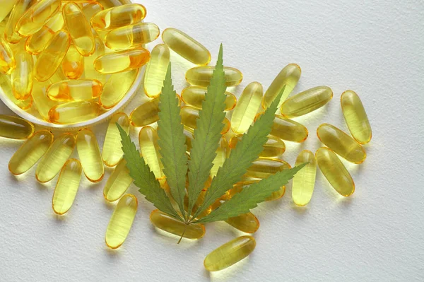 Tıbbi esrar ürünleri, yaprak, kapsüller beyaz arka planda CBD yağı. Biyolojik bitkisel bitkilerle birlikte jelatin softgeller. Organik beslenme takviyeleri kavramı