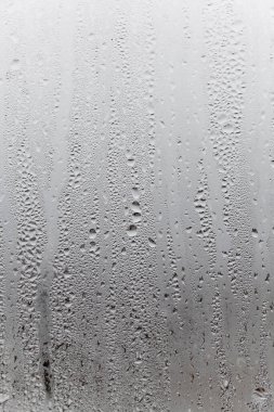 Camda damlaların aktığı bir yoğunluk, dikey doğal arka plan, nem ve sisli boşluk. Dışarıda, kötü hava, yağmur...