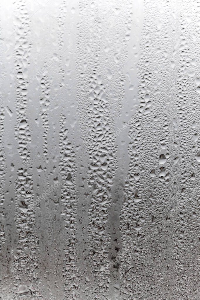 Vertical natural background, condensation on glass with drops flowing down, humidity and foggy blank. Outside , bad weather, rain