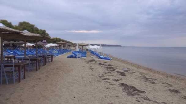 저녁에는 모래사장 그리스의 해변에서 파란색 의자와 일광욕을 즐기는 침대가 널빤지 — 비디오