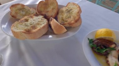 Sos, ahtapot ve beyaz masa örtüsü olan bir restoran masasında çıtır kalamar deniz ürünleri..