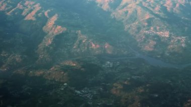 Çerçevenin sağına bakarak, dağ sırasının üzerinde uçarak seyahat edin. Yolcu engellenmemiş nehir manzarası tepe evleriyle kırsal alanda yüksek irtifada seyreden bir uçağa biniyor..