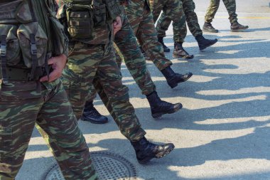 Tören sırasında savaş üniformalı Yunan askerleri. Yunan Silahlı Kuvvetleri silueti. Siyah çizme giyen ve kamuflaj desenli savaş kıyafetleri giyen erkekler..