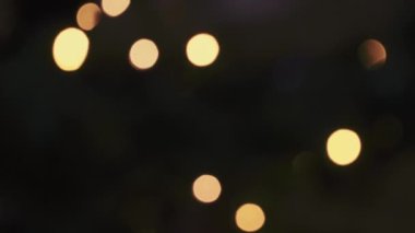 Bokeh koyu arkaplana karşı gerçek ışıklara odaklanamadı. Altın rengi bulanık yuvarlak şekiller tekrarlanan bir desen üzerinde sürekli yanıp sönüyor.. 