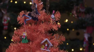 Yapay turuncu Noel ağacı. Odaklanamayan arka planda süsleri var. Tahta şenlik minyatürleri rengarenk dallarda asılı, aydınlatıcı ışıklarla..