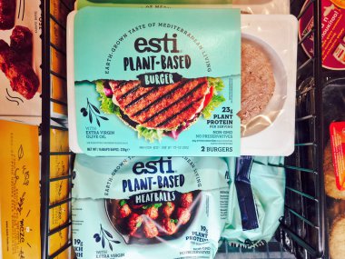  Bitki bazlı vegan eti süpermarkette satışta. Bir süpermarkette soğutulmuş, içinde esti vejetaryen burgerler ve köfteler olan paketlerin iç görünümünü depolayın..