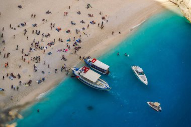 Zakynthos, Yunanistan. Kristal berrak suları olan Navagio Batık Plajı. Bir zamanlar dünyanın en iyisi olarak seçilen ünlü İyon Adası plajında demirli tekne ve yüzücülerin panoramik manzarası..