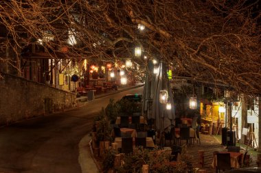 Arcadia Moreloponnese 'deki Lagadia' da boş bir gece sokağındaki büyük ağaç dallarının altındaki açık kafe ve Yunan taverna oturma alanı.