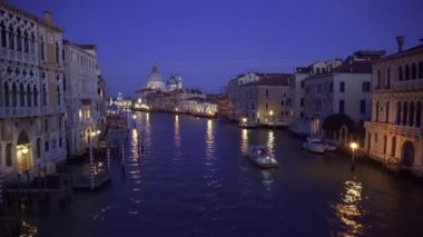 Venedik İtalya, Büyük Kanal 'ın sakin sularında yelkenli gemi manzarası Basilica di Santa Maria della Salute ve Dorsoduro bölgesinde aydınlatılmış geleneksel binalar..