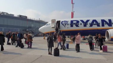 Napoli, İtalya NAP uluslararası havaalanı yolcuları apron bölgesinde bavul taşıyarak, bir Boeing 737 Ryanair uçağı indiriyorlar..