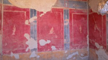 Panning inside colorful wall decoration of a house with Roman frescoes in the archaeological area of Pompeii, Italy.