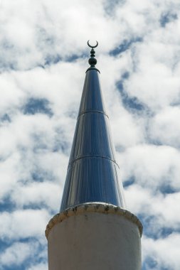 Day low angle view of Islamic Culture mosque minaret tower with a finial on top, against sky with dense clouds.