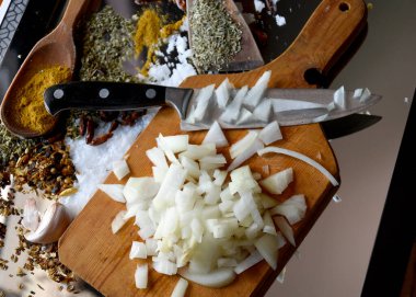 Vejetaryen yemeği pişirmek için tahtanın üzerinde bıçakla doğranmış soğan.