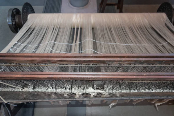 Old loom, spinning machine, rows of white and colored cotton threads