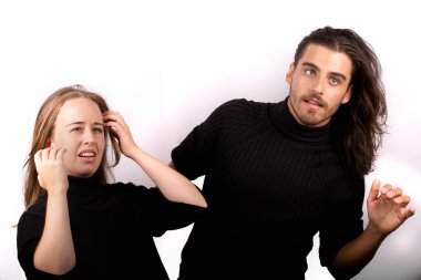 Siyah kazaklı genç ve güzel sarışın kadın ve siyah kazaklı yakışıklı bir adam beyaz arka planda komik jestler yapıyor.-