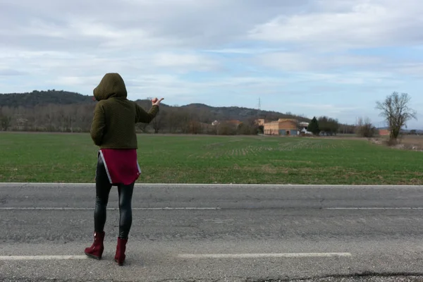 Sisli bir günde bavulu yol boyunca sürükleyen bir kadın.