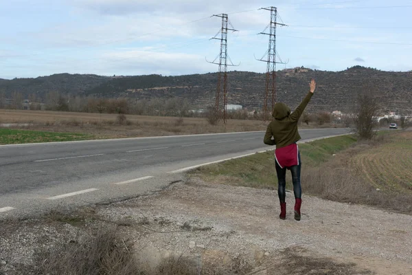 Sisli bir günde bavulu yol boyunca sürükleyen bir kadın.