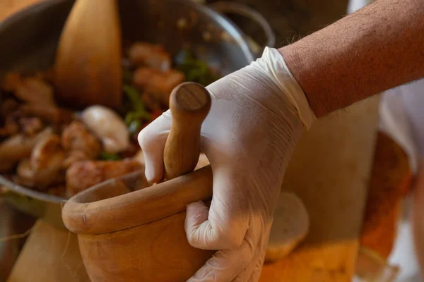 Havan ve eldivenli eller yemek güveci pişiriyor.