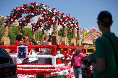 CORDOBA,SPAIN - 2 May. 2022: Battle of the flowers, Women dressed in traditional flamenco dress on cart throwing flowers to the public in the Battle of Flowers parade, which marks the start of Cordoba