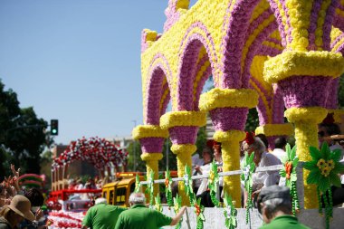 CORDOBA,SPAIN - 2 May. 2022: Battle of the flowers, Women dressed in traditional flamenco dress on cart throwing flowers to the public in the Battle of Flowers parade, which marks the start of Cordoba