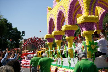 CORDOBA,SPAIN - 2 May. 2022: Battle of the flowers, Women dressed in traditional flamenco dress on cart throwing flowers to the public in the Battle of Flowers parade, which marks the start of Cordoba