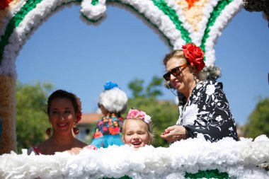 Cordoba, İspanya - 2 Mayıs. 2022: Çiçek Savaşı: Geleneksel flamenko elbiseli kadınlar, Cordoba 'nın başlangıcı olan Çiçekler Savaşı' nda halka çiçek atıyor.