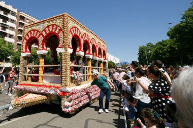 CORDOBA,SPAIN - 2 May. 2022: Battle of the flowers, Women dressed in traditional flamenco dress on cart throwing flowers to the public in the Battle of Flowers parade, which marks the start of Cordoba