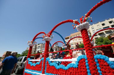CORDOBA,SPAIN - 2 May. 2022: Battle of the flowers, Women dressed in traditional flamenco dress on cart throwing flowers to the public in the Battle of Flowers parade, which marks the start of Cordoba