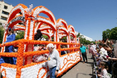 CORDOBA,SPAIN - 2 May. 2022: Battle of the flowers, Women dressed in traditional flamenco dress on cart throwing flowers to the public in the Battle of Flowers parade, which marks the start of Cordoba