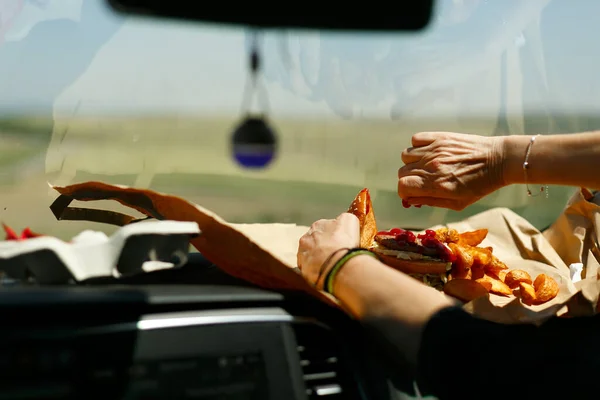 Womans hands eating a hamburger inside a car, fast food — 스톡 사진