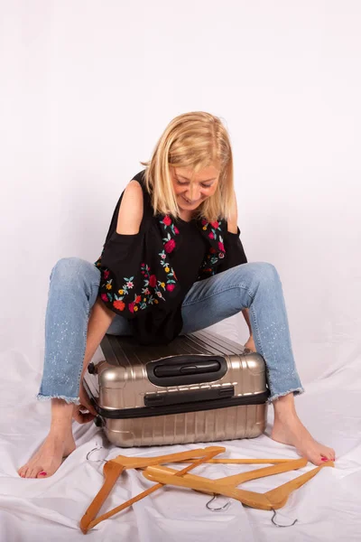 Dorosła kobieta pakująca walizkę na wyjazd, wakacje, białe tło — Zdjęcie stockowe