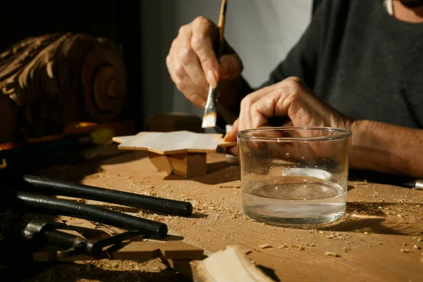 Las manos de un carpintero pintando una estrella de madera, irreconocible. —  Fotos de Stock