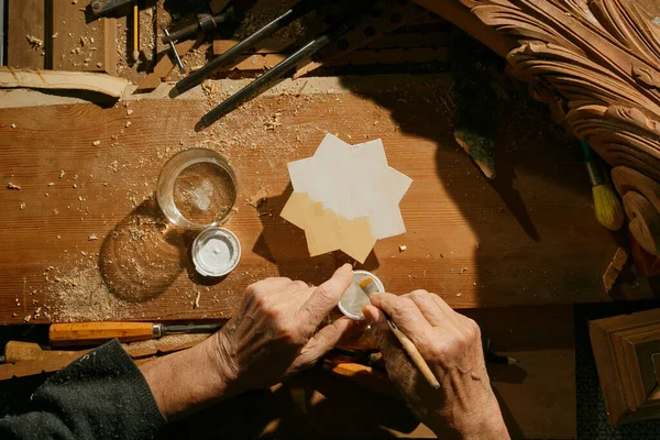 Las manos de un carpintero pintando una estrella de madera, irreconocible. — Foto de Stock