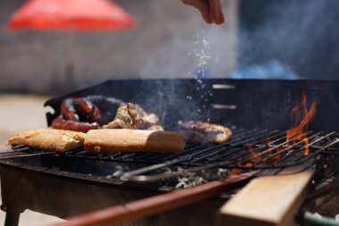 Güneşli bir günde, ev yapımı barbeküde elinde maşayla ekmek kızarttım.,