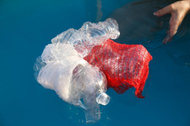 Kadın eli kaldırır ve plastik şişeler su üstünde yüzer, plastik kirlilik