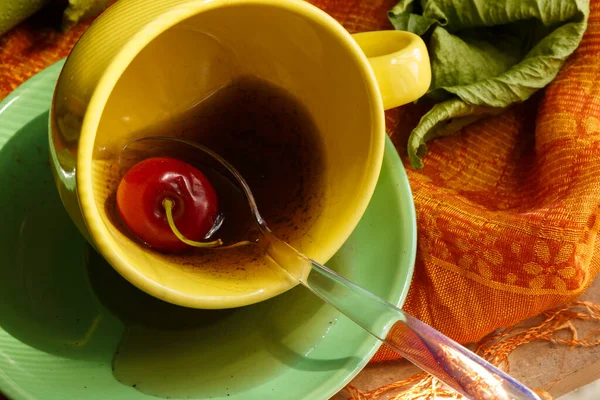 Sarı kahve fincanı içinde kiraz, kenarında kahve, gastronomik fotoğraf.