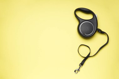 Black retractable dog leash on a yellow background, space for text. Flat lay. clipart