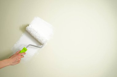 Erkek dekoratör duvarları kapalı kapılar ardında boyuyor. Metin için boşluk.