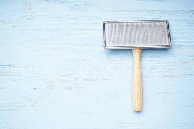 Yün yetiştirmek için fırça. Mavi ahşap zemin üzerinde köpekler için fırça, düz uzanma, metin için boşluk.