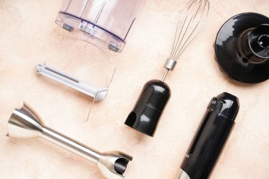 Bej arka planda farklı eklentilere sahip daldırma el blenderi, yakın plan. El karıştırıcı seti, üst görünüm.