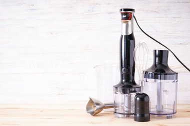 Siyah plastik elektrikli el blendırı, paslanmaz çelik gövde ve ahşap arka planda aksesuar, metin için alan.