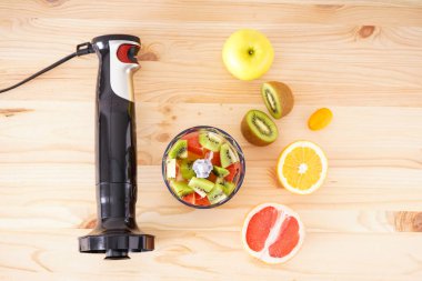 Siyah plastik el blendırı ve aksesuarları tahta bir arka planda dilimlenmiş meyve, düz yatıyordu..