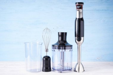 Siyah plastik elektrikli el blenderi, paslanmaz çelik gövdesi ve gri arka planda aksesuarı var..