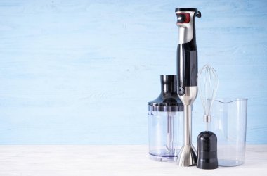 Siyah plastik elektrikli el blendırı, paslanmaz çelik gövde ve ahşap arka planda aksesuar, metin için alan.