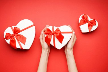 Kırmızı arka planda Sevgililer Günü için hediye kutulu kadın elleri. Üst Manzara. Aşk ve Sevgililer Günü kavramı.