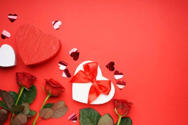 Sevgililer günü için hediye kutusu ve kırmızı arka planda güller ve mesaj için yer. Üst görünüm.