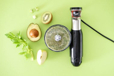 Siyah plastik el blendırı ve yeşil arka planda meyveli aksesuarlar. Düz yatıyordu.