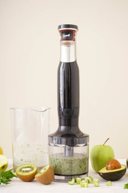 Siyah plastik el blendırı ve aksesuarlarla dilimlenmiş meyve rengi arka planda.
